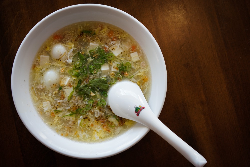 A dimly lit bowl of soup shot from above with inconsistent lighting