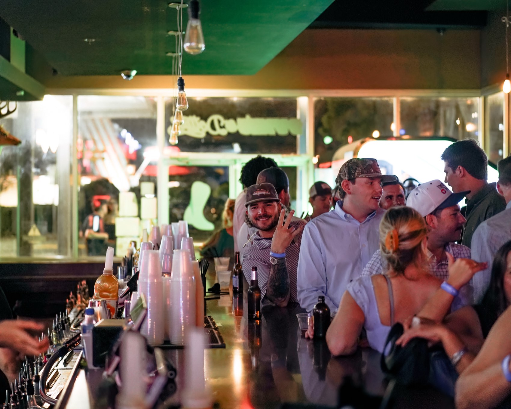 A packed bar crowd laughing and talking as a bartender works the taps