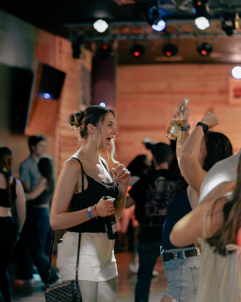 A guest laughing and raising a drink on a busy night