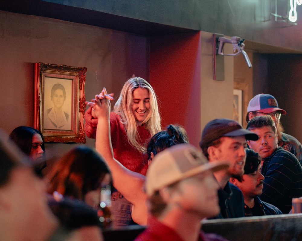 A guest dancing under red and neon lighting at a Denver bar