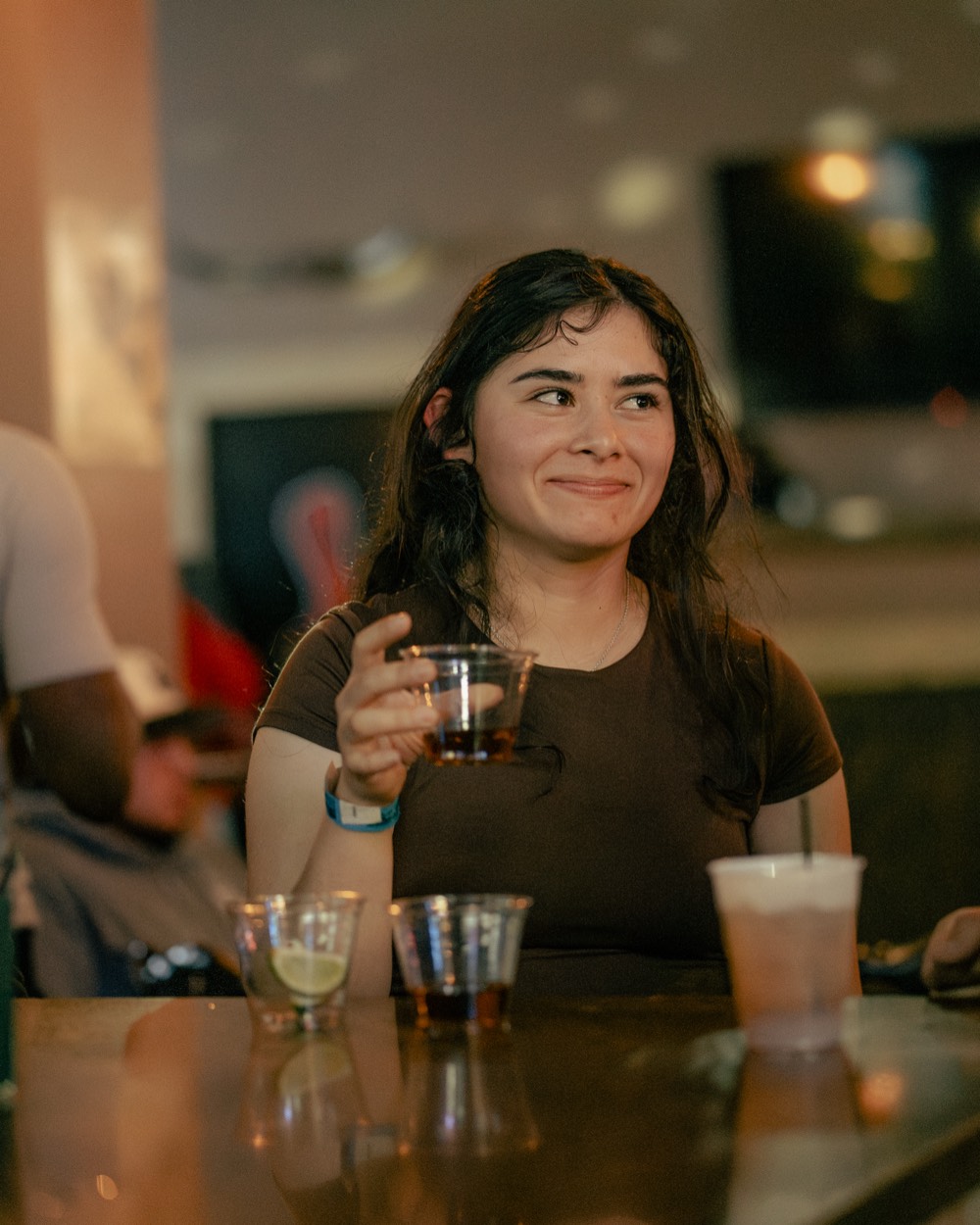 A guest smiling with a cocktail in hand at the bar