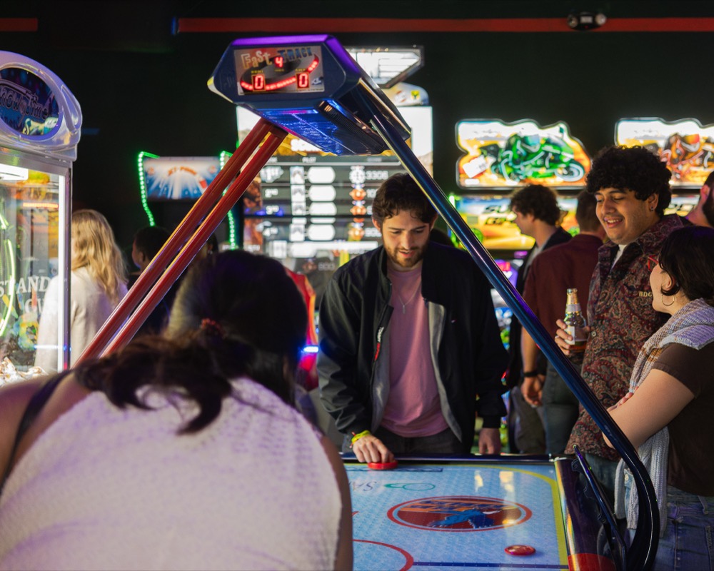 A group of friends laughing together at an arcade game
