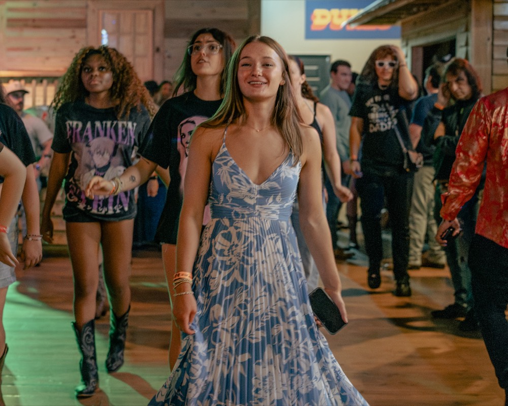 A dressed-up crowd entering a colorful, lively venue